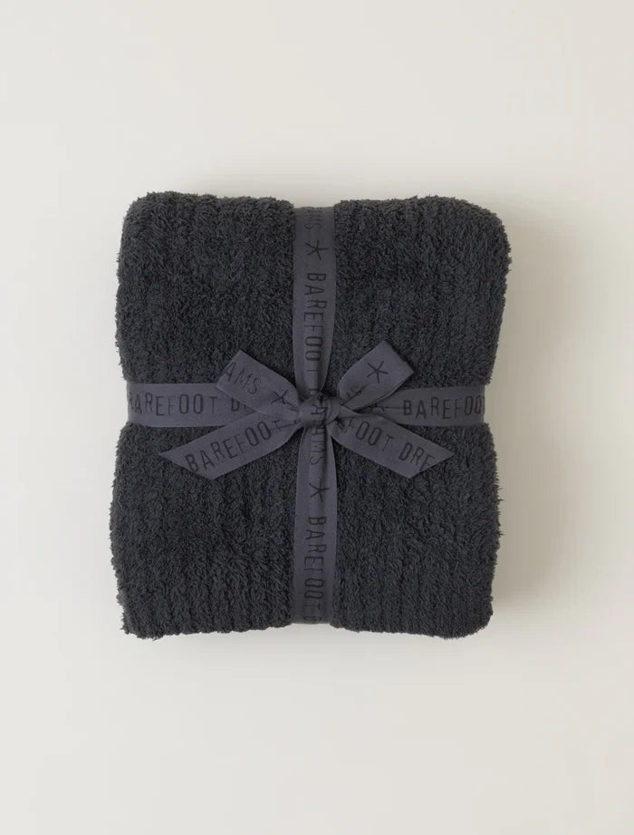 black plush pinched striped blanket tied with matching barefoot dreams ribbon against a neutral background