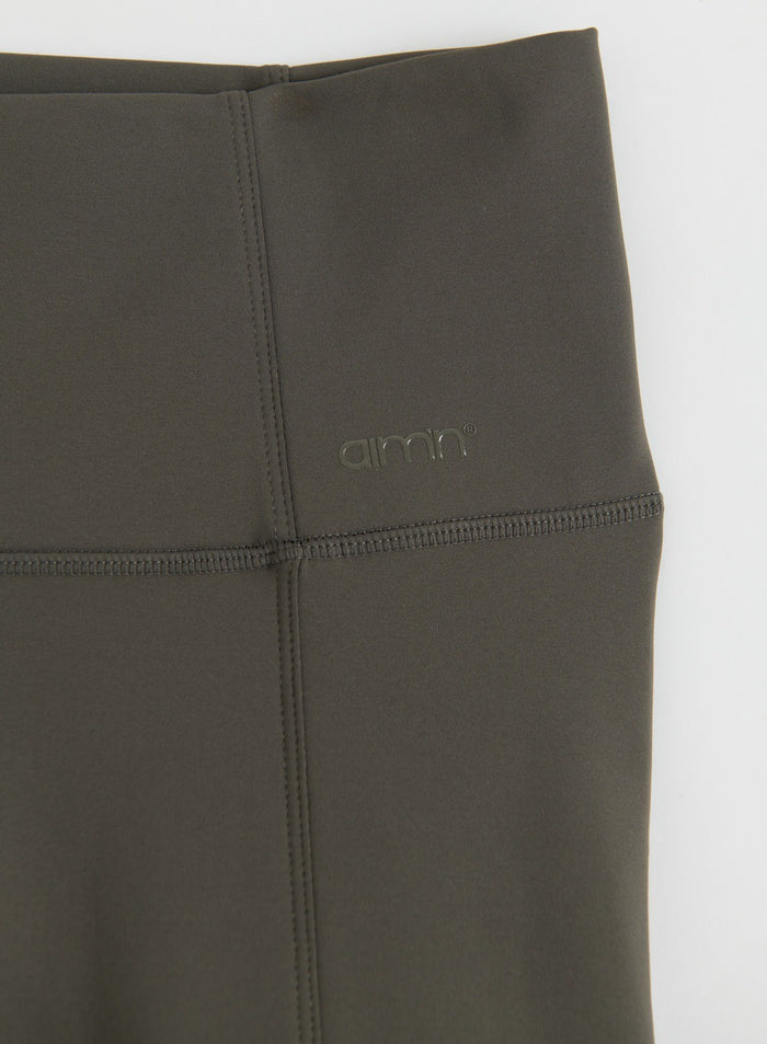 Close-up of dark ivy warming pocket tights showing the high waistband, stitching and aim'n logo