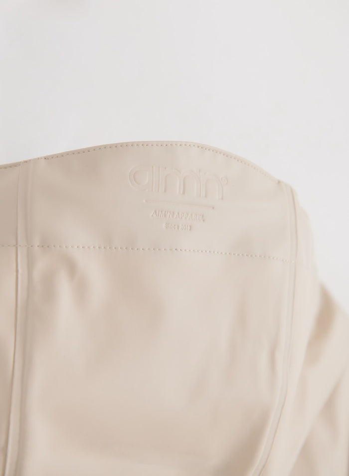 Close-up of the sand rain jacket showing the aim'n logo detail