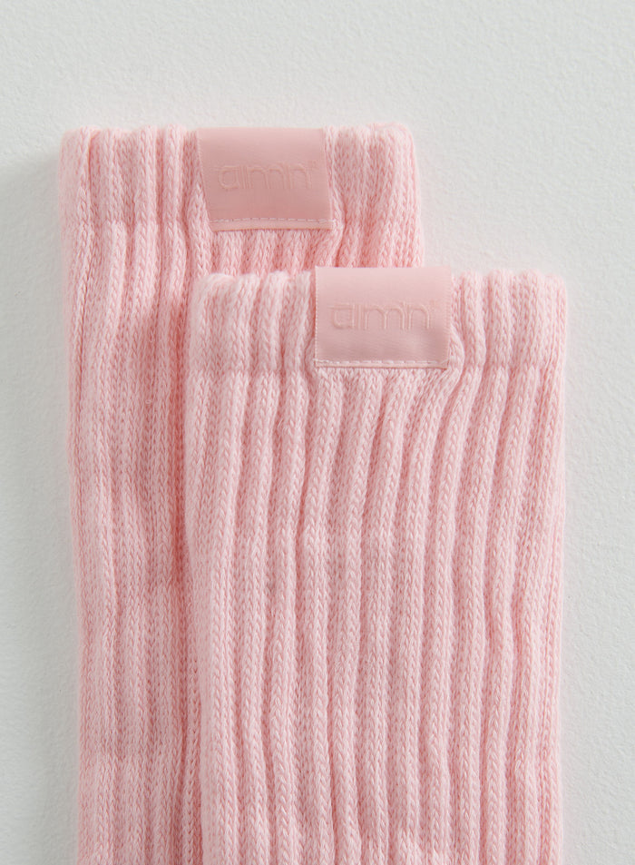 Close-up of pink ribbed Slouch Socks with a discreet aim'n logo badge