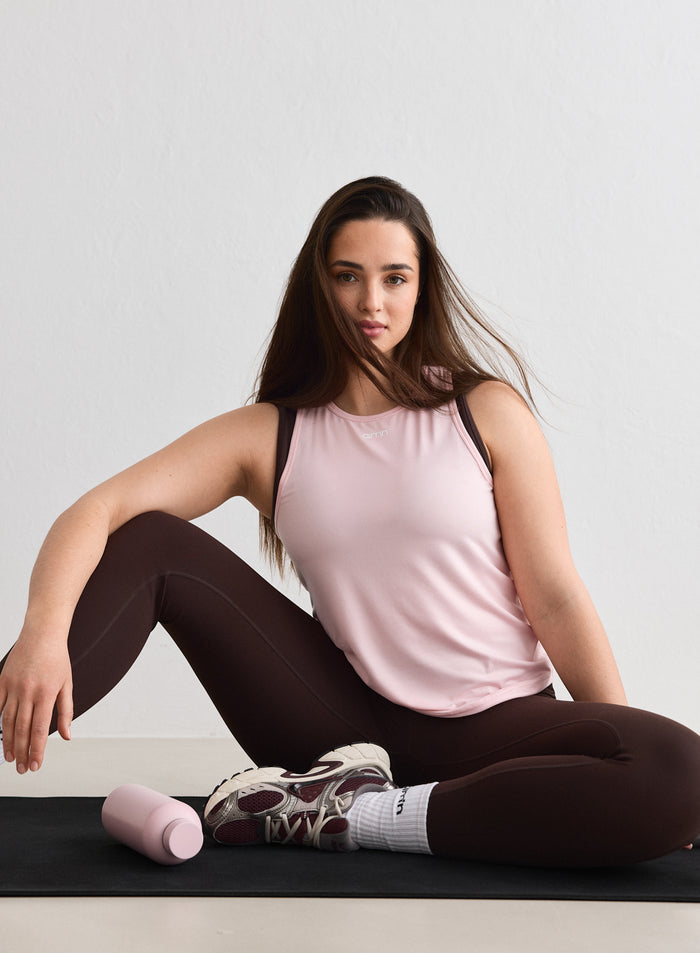 A woman wearing a pink Ballerina Soft Basic Singlet from aim'n while sitting on a yoga mat [L-174cm]