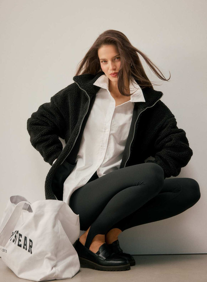 Black high-waisted Sense Stirrup Tights by aim'n styled with a fleece jacket and white shirt.