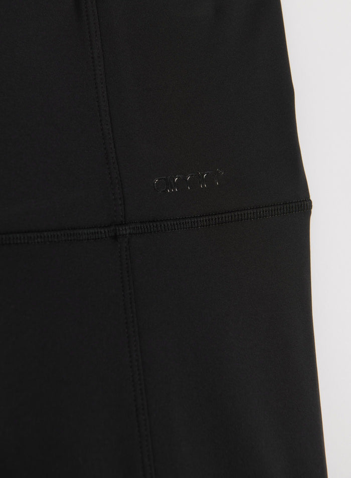 Close-up of black warming tights showing stitched seams and a tonal aim'n logo