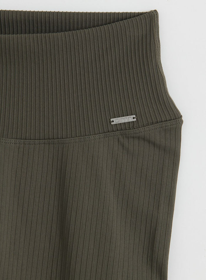 Close-up flatlay of dark ivy ribbed seamless tights with a high waistband, ribbed texture and aim'n logo