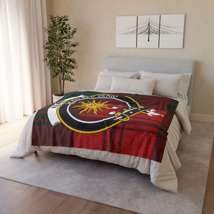 Kerr printed throw on a bed with sun crest over a tartan background