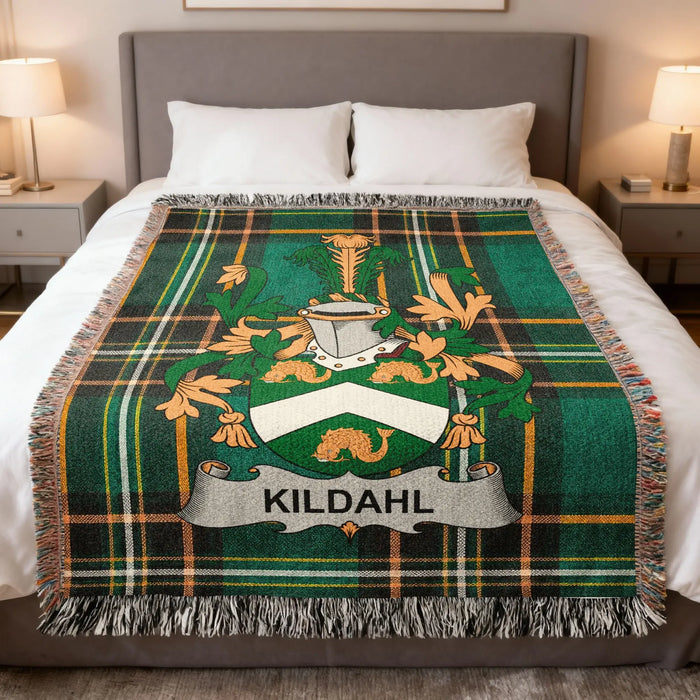 Kildahl family crest on a green plaid blanket with tassels, on a bed.