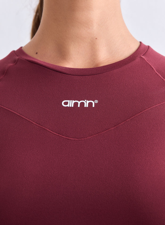 Close-up of the merlot Soft Basic Short Sleeve showing the round neck and white aim'n logo. [S-165cm]
