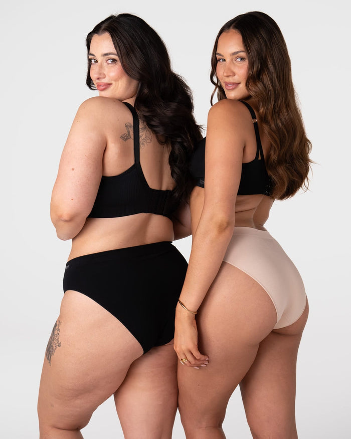 Two models wearing the Hotmilk My Necessity Seamless Bikini Briefs – rear view showing Black and Frappe colourways and mid-coverage fit across two different body shapes, paired with the My Everyday Nursing Bra in Black