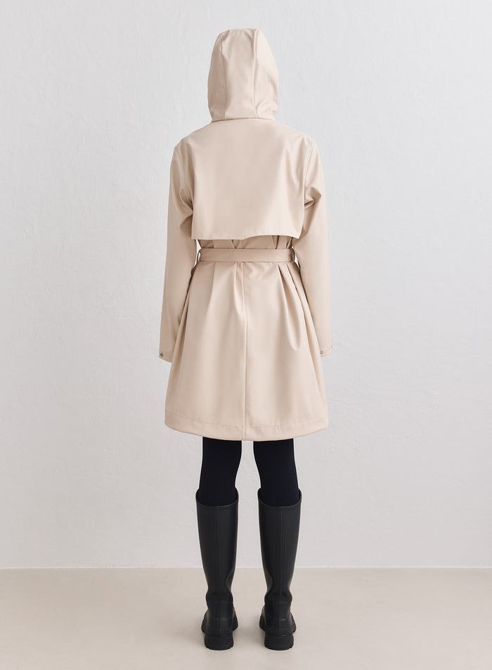 Rear view of a sand-colored aim'n rain jacket featuring a belted waist and back ventilation yoke. [M-178cm]