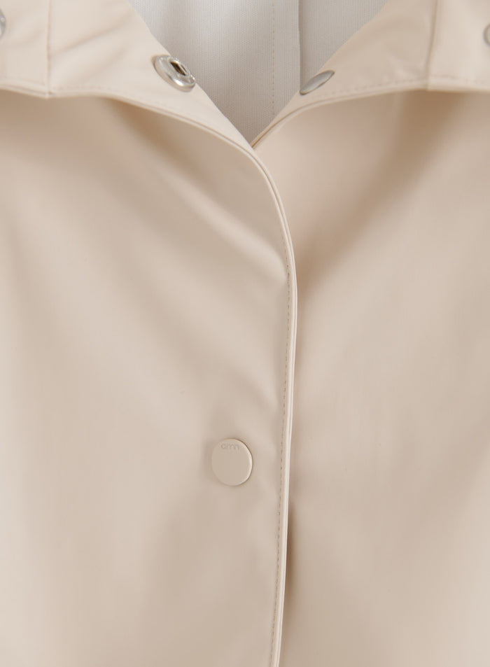 Close-up of the snap button and collar details on the sand-colored aim'n Rain Jacket