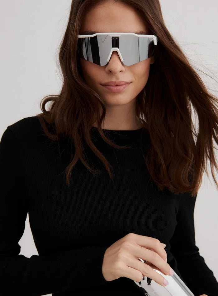Silver mirrored Pace Sunglasses with a white frame worn by a woman in a black ribbed top by aim'n.