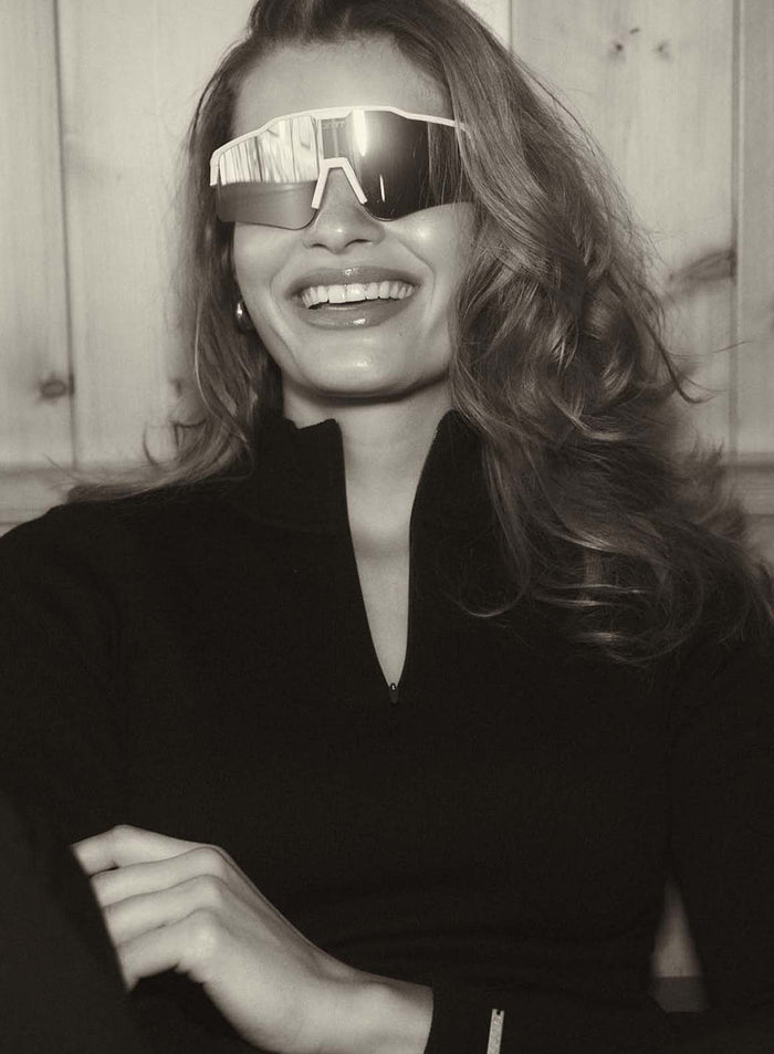 Mirrored silver Pace Sunglasses worn by a smiling woman in a black zip-up top by aim'n.