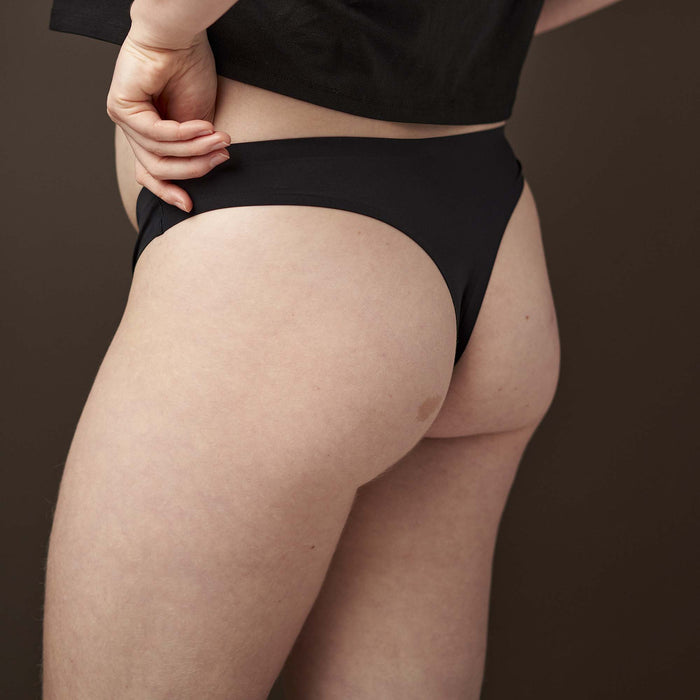Person wearing black underwear and a black shirt on a brown background